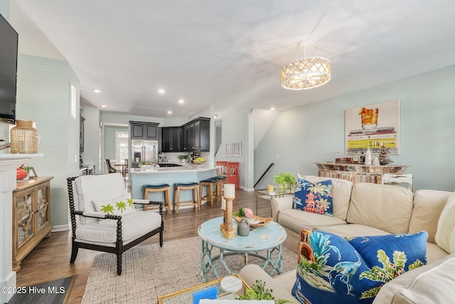 living area featuring recessed lighting, baseboards, an inviting chandelier, and light wood-style flooring