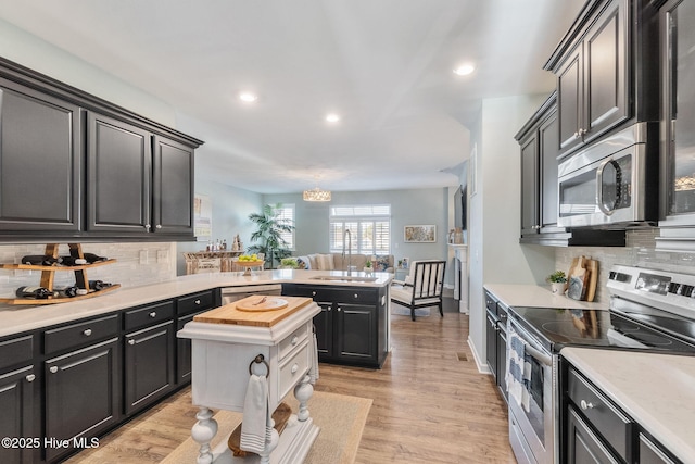 kitchen with a sink, tasteful backsplash, appliances with stainless steel finishes, and a peninsula