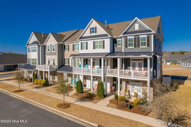 townhome / multi-family property featuring a standing seam roof, a balcony, a residential view, and metal roof