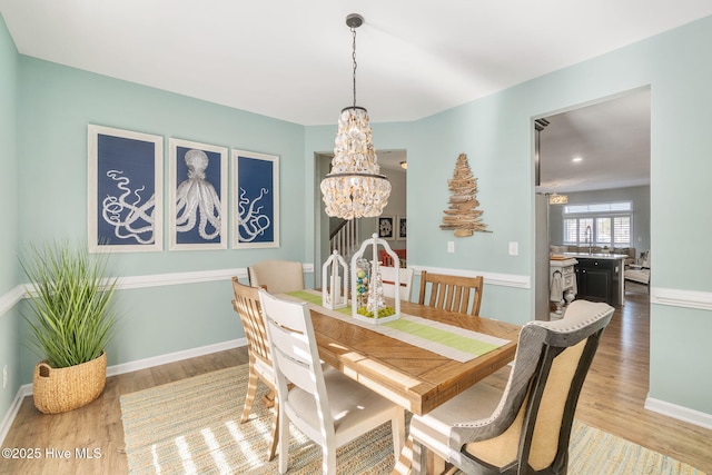 dining space with a chandelier, baseboards, and wood finished floors