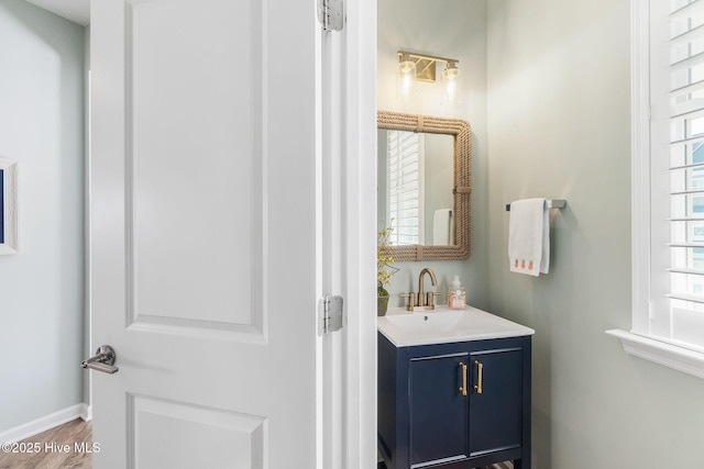 bathroom with vanity, wood finished floors, baseboards, and a wealth of natural light