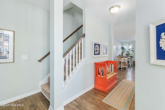 staircase featuring wood finished floors and baseboards