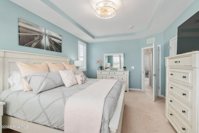 bedroom with light carpet, visible vents, a raised ceiling, and baseboards