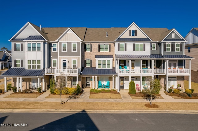 townhome / multi-family property with a residential view, metal roof, a standing seam roof, and stone siding