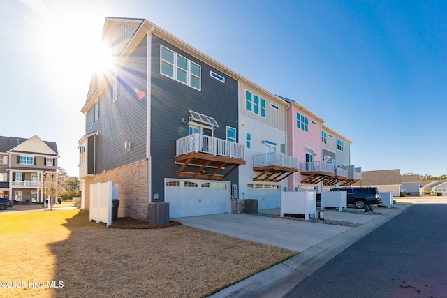 rear view of house featuring a residential view, a garage, concrete driveway, and central AC