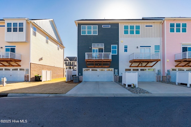 rear view of house featuring central air condition unit, an attached garage, concrete driveway, and board and batten siding