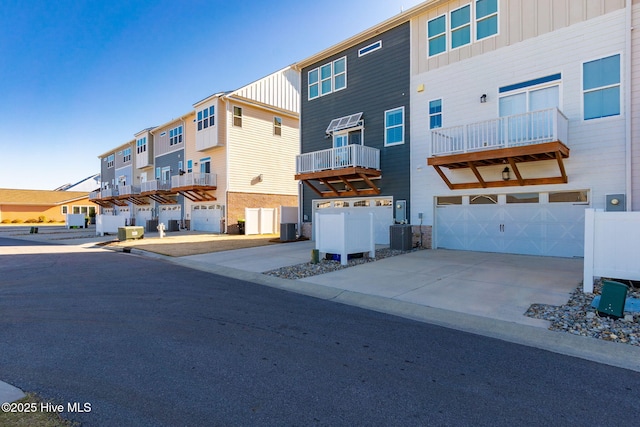 exterior space with board and batten siding, a residential view, cooling unit, driveway, and an attached garage