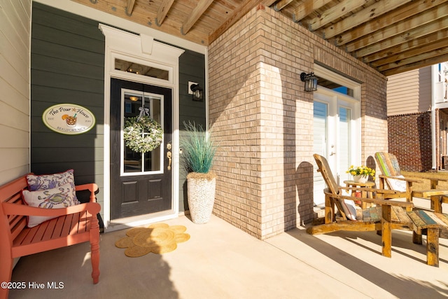 doorway to property featuring brick siding and a porch