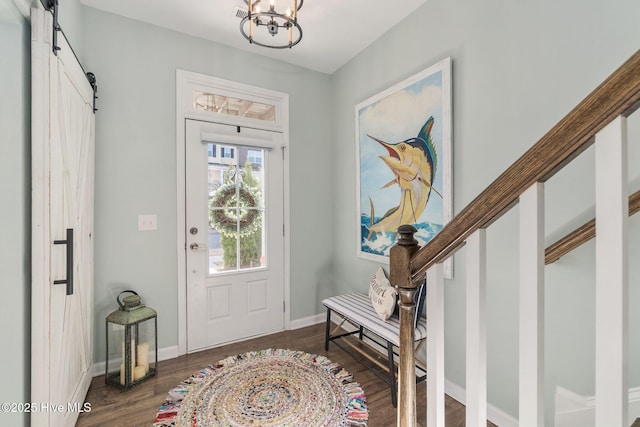 foyer entrance with a chandelier, baseboards, a barn door, and wood finished floors