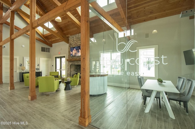 interior space featuring visible vents, beam ceiling, high vaulted ceiling, wood finished floors, and wooden ceiling