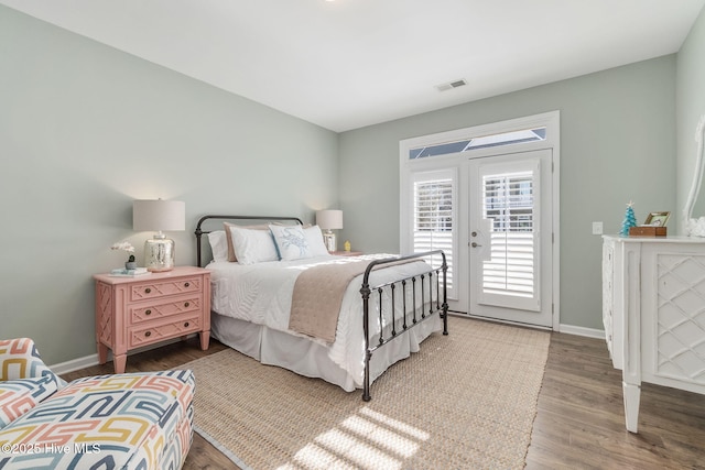 bedroom featuring access to outside, wood finished floors, visible vents, and baseboards