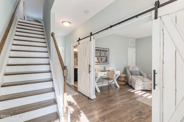 stairway with a barn door, visible vents, and wood finished floors