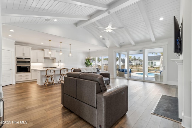 living room with a wealth of natural light, wood finished floors, and lofted ceiling with beams