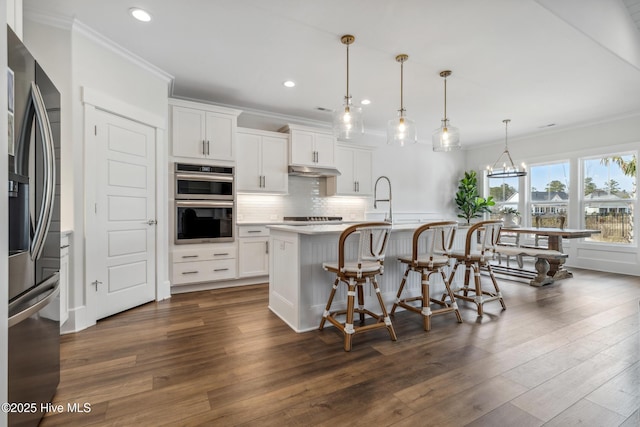 kitchen featuring stainless steel appliances, under cabinet range hood, crown molding, and recessed lighting