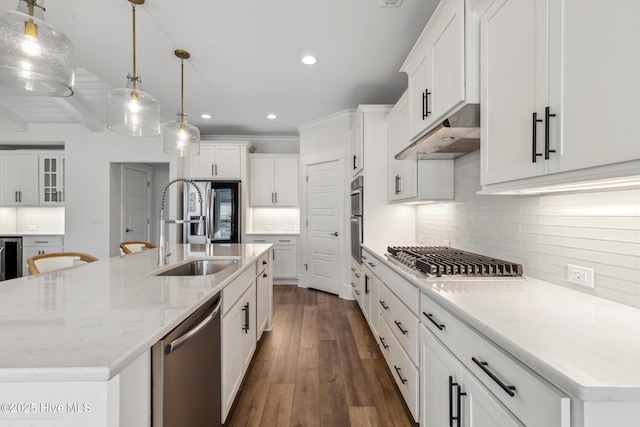 kitchen with recessed lighting, appliances with stainless steel finishes, under cabinet range hood, a sink, and decorative backsplash