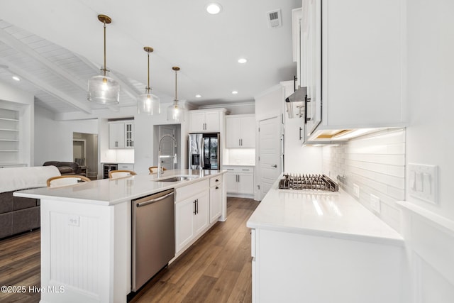 kitchen featuring white cabinets, a sink, open floor plan, stainless steel appliances, and decorative backsplash