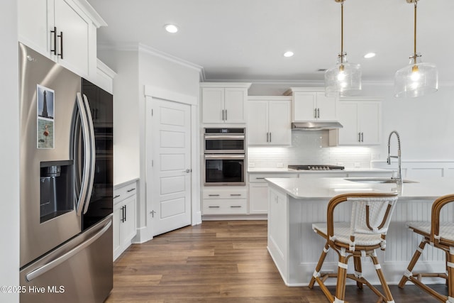 kitchen featuring tasteful backsplash, ornamental molding, appliances with stainless steel finishes, under cabinet range hood, and light countertops