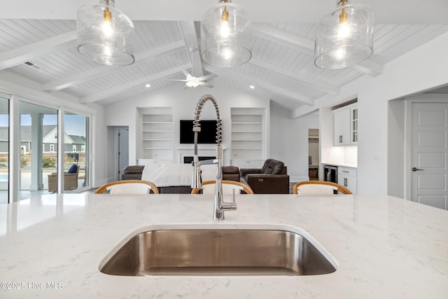 kitchen with open floor plan, a sink, built in features, and light stone counters