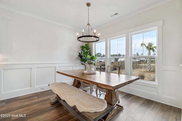 dining room featuring a chandelier, plenty of natural light, crown molding, visible vents, and a decorative wall
