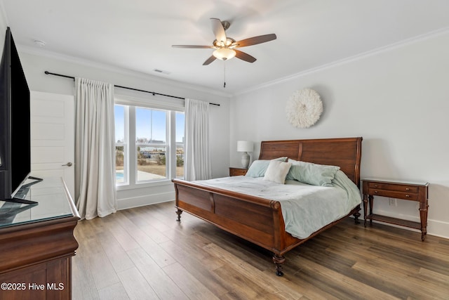bedroom featuring a ceiling fan, wood finished floors, ornamental molding, and visible vents