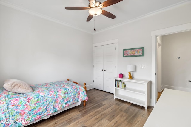 bedroom featuring crown molding, a closet, a ceiling fan, wood finished floors, and baseboards