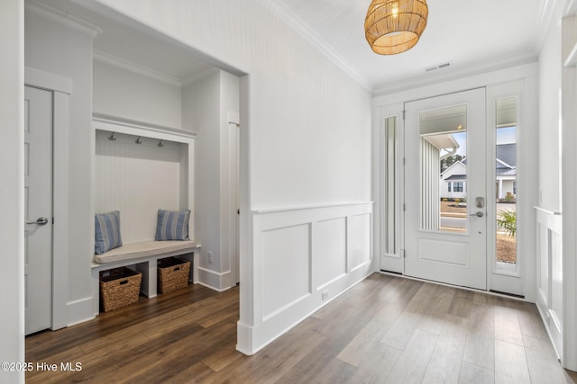 entryway featuring crown molding, a decorative wall, visible vents, wood finished floors, and wainscoting