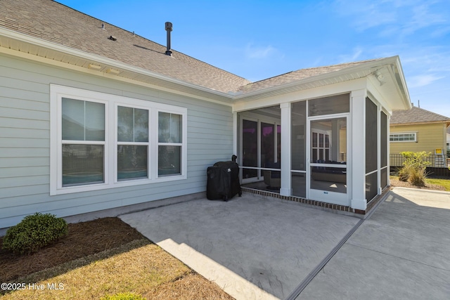 rear view of property featuring a sunroom, a patio, fence, and roof with shingles