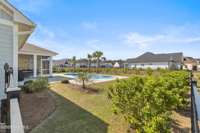 view of swimming pool with a sunroom, a fenced backyard, a residential view, and a lawn