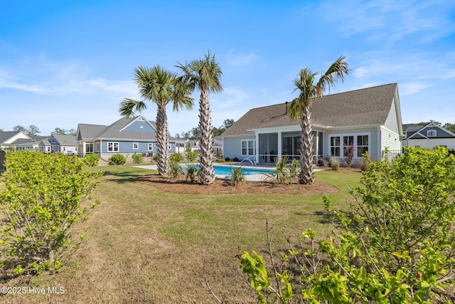 back of house featuring an outdoor pool, a sunroom, and a lawn