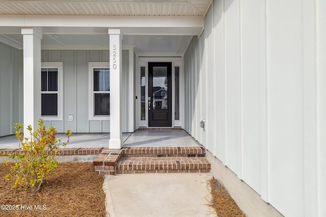 view of exterior entry with a porch and board and batten siding