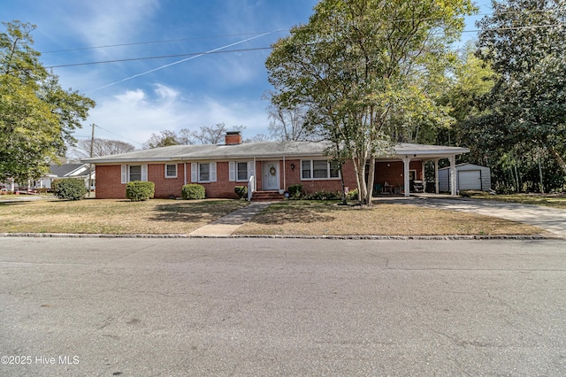 ranch-style house featuring an outbuilding, driveway, a front yard, brick siding, and a chimney