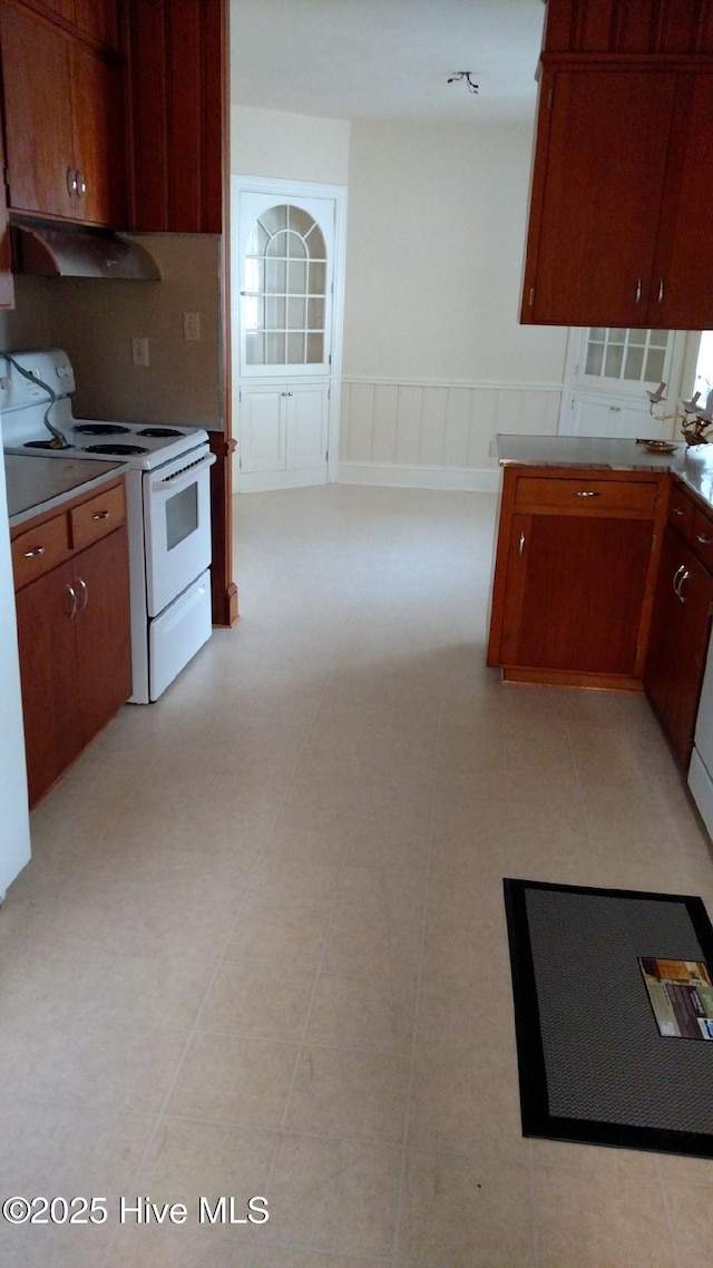 kitchen with under cabinet range hood, electric range, and wainscoting