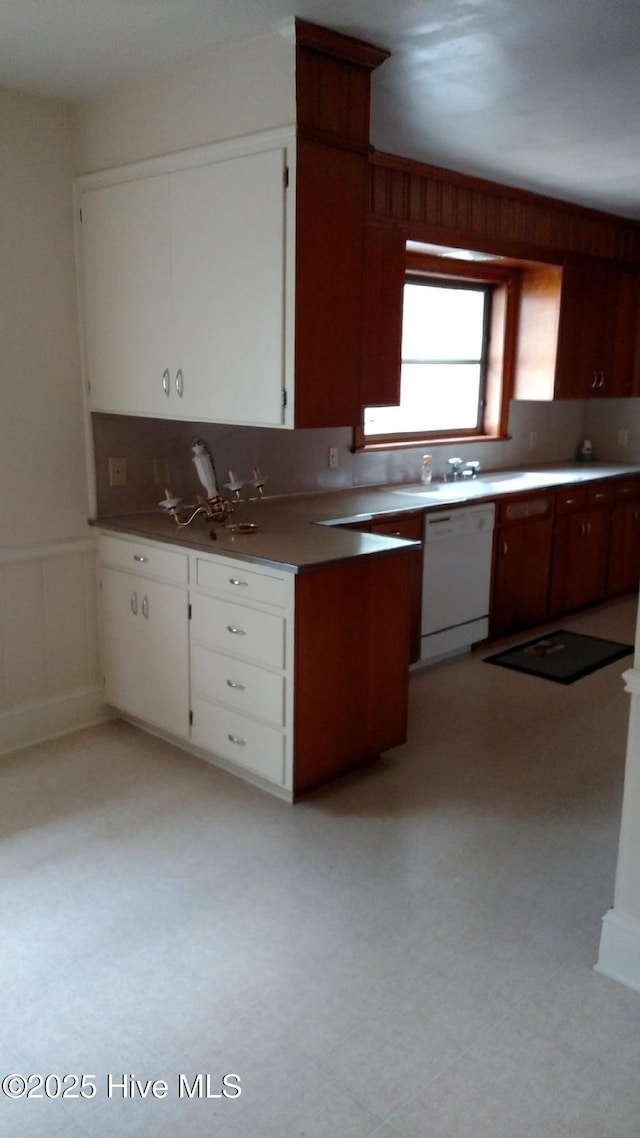 kitchen featuring a wainscoted wall, white cabinetry, decorative backsplash, light floors, and dishwasher