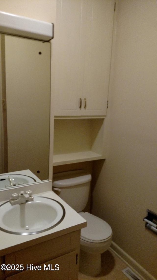 half bathroom featuring vanity, toilet, baseboards, and visible vents