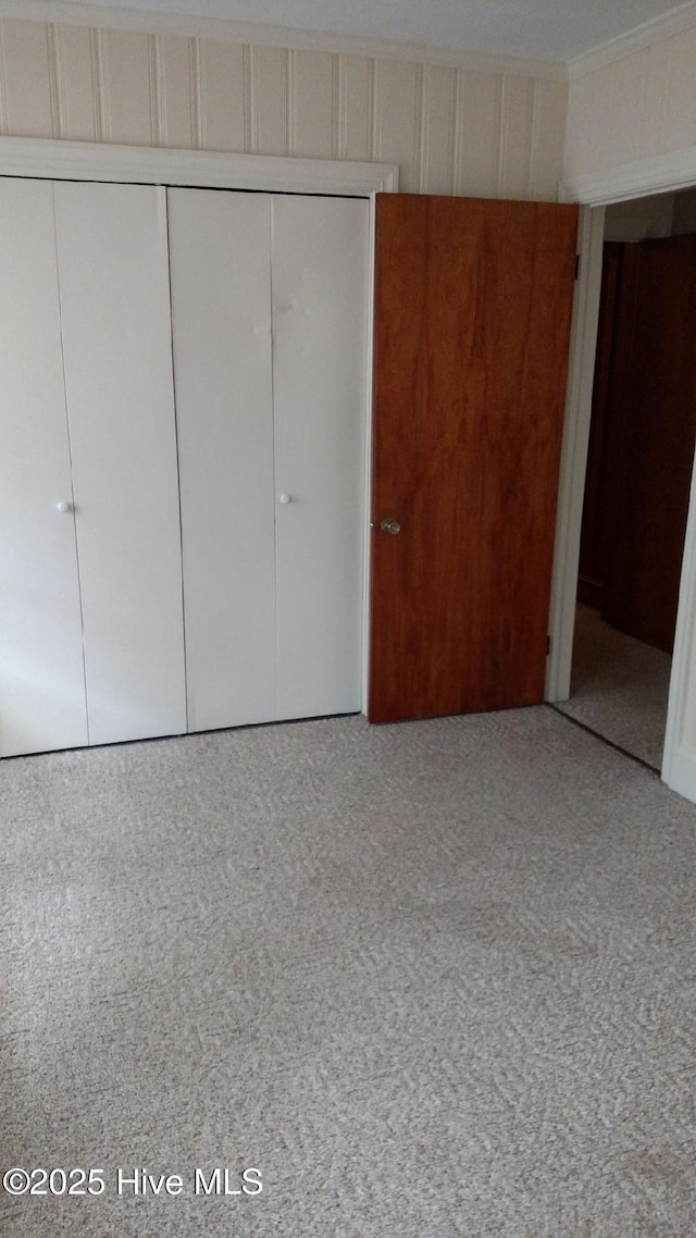 unfurnished bedroom featuring a closet, carpet floors, and ornamental molding