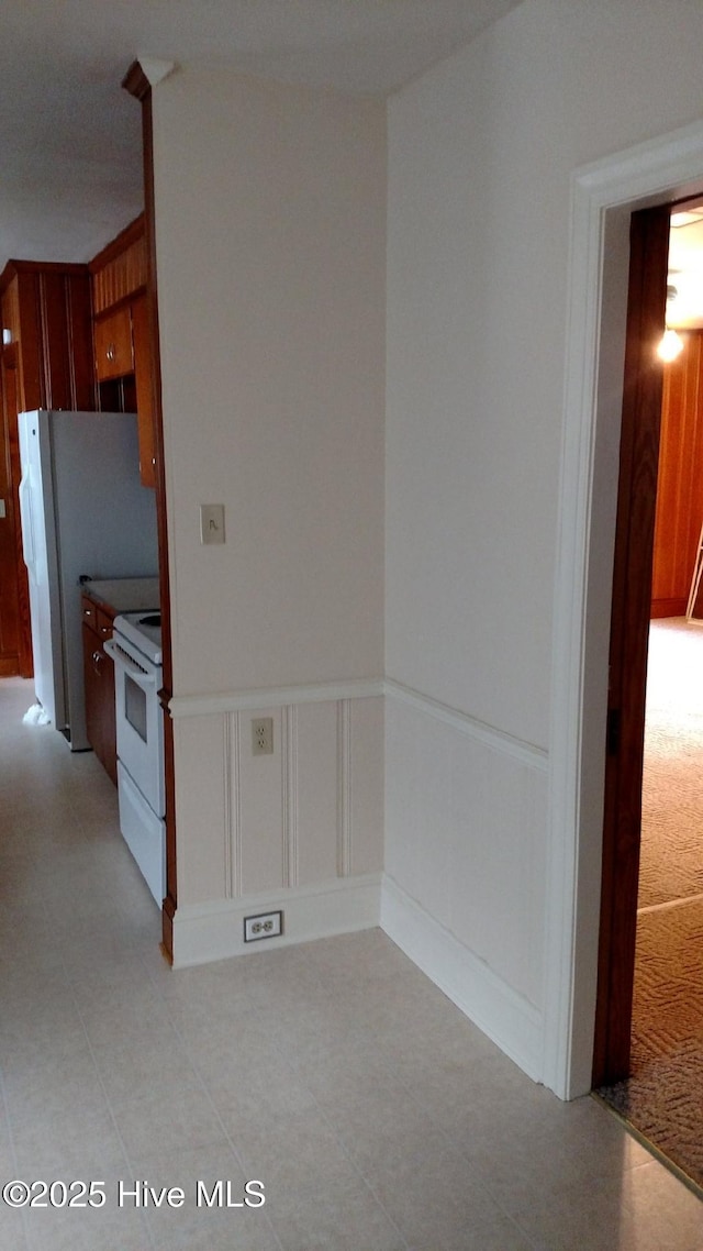 kitchen featuring a wainscoted wall, white appliances, and a decorative wall