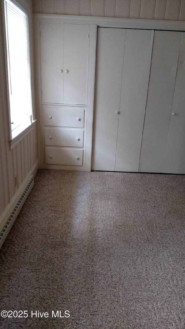 unfurnished bedroom featuring a baseboard heating unit and a closet