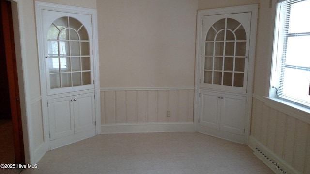 unfurnished room featuring a wainscoted wall and a healthy amount of sunlight