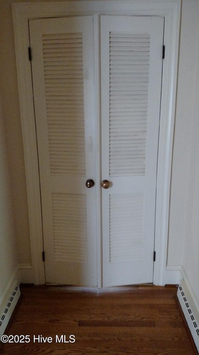 room details featuring a baseboard heating unit and wood finished floors