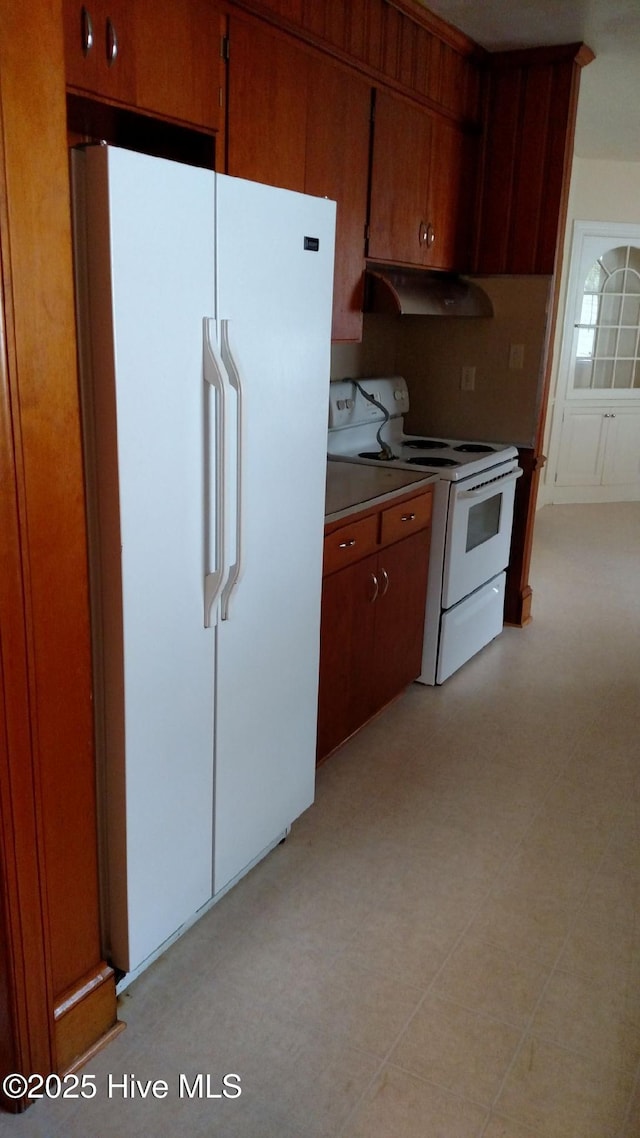 kitchen featuring white appliances, light floors, light countertops, under cabinet range hood, and brown cabinets