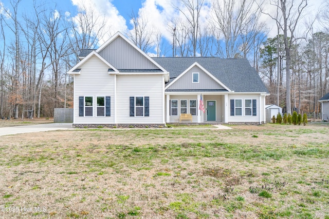 view of front of house featuring a porch, board and batten siding, a front lawn, and roof with shingles