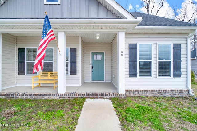 view of exterior entry with a porch and roof with shingles