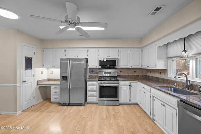 kitchen with visible vents, light wood-style floors, white cabinets, stainless steel appliances, and a sink