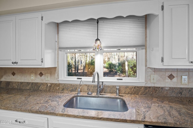 kitchen with white cabinetry, backsplash, and a sink