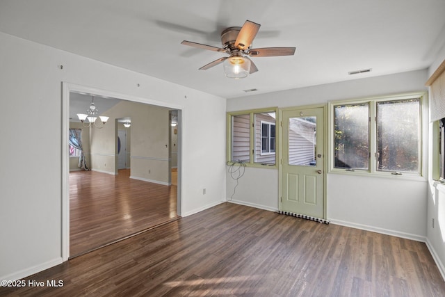 empty room with visible vents, baseboards, wood finished floors, and ceiling fan with notable chandelier