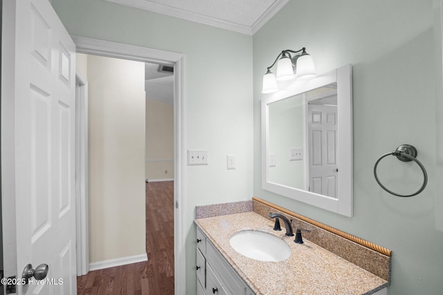 bathroom with visible vents, baseboards, ornamental molding, wood finished floors, and vanity