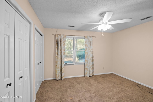 unfurnished bedroom featuring baseboards, visible vents, two closets, and carpet