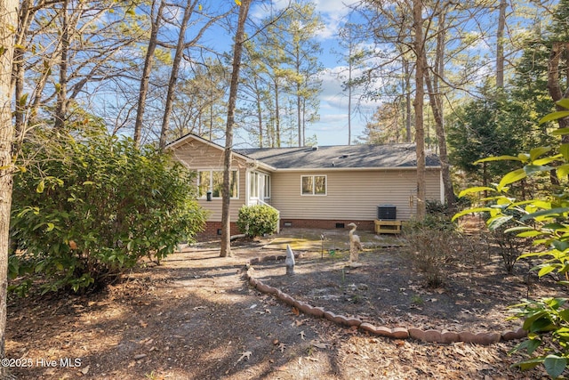 back of property featuring crawl space, central AC unit, and a shingled roof