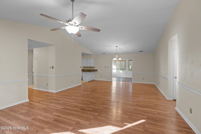 unfurnished living room featuring baseboards, light wood-style floors, high vaulted ceiling, and ceiling fan with notable chandelier