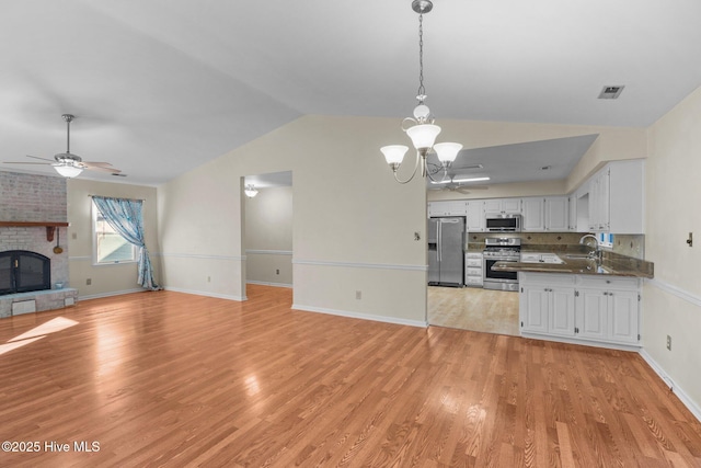 kitchen featuring visible vents, a sink, stainless steel appliances, light wood-style floors, and open floor plan